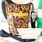 Eyeglasses hang from an unzipped pocket of a purple & yellow swirl print water bottle bag. Yellow fabric peeks out from the unzipped pocket.